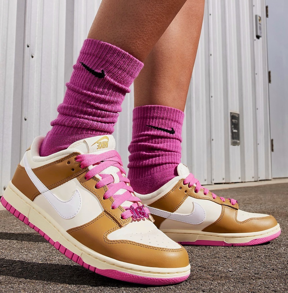 Nike Dunk Low SE is deisgned for women in Bronzine and Playful Pink color. There are metallic Just Do It dubraes on laces. You can also find the reversed Nike logos on heel tabs.